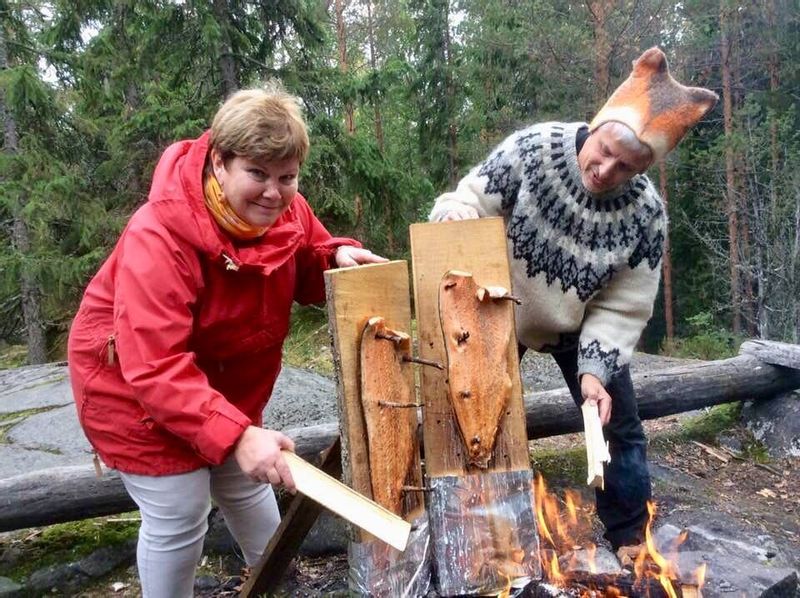 Southern Finland Private Tour - preparing flamed salmon to our clients in the forest