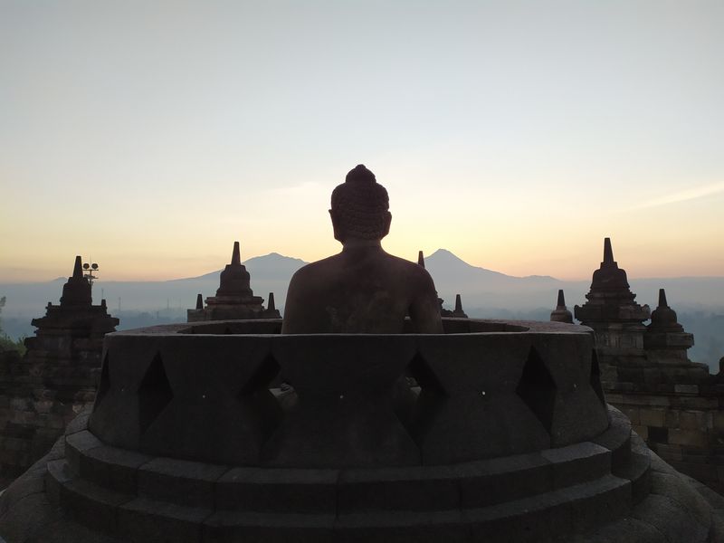 Yogyakarta Private Tour - A Buddhist Statue in the half uncovered Stupa at Borobudur Temple