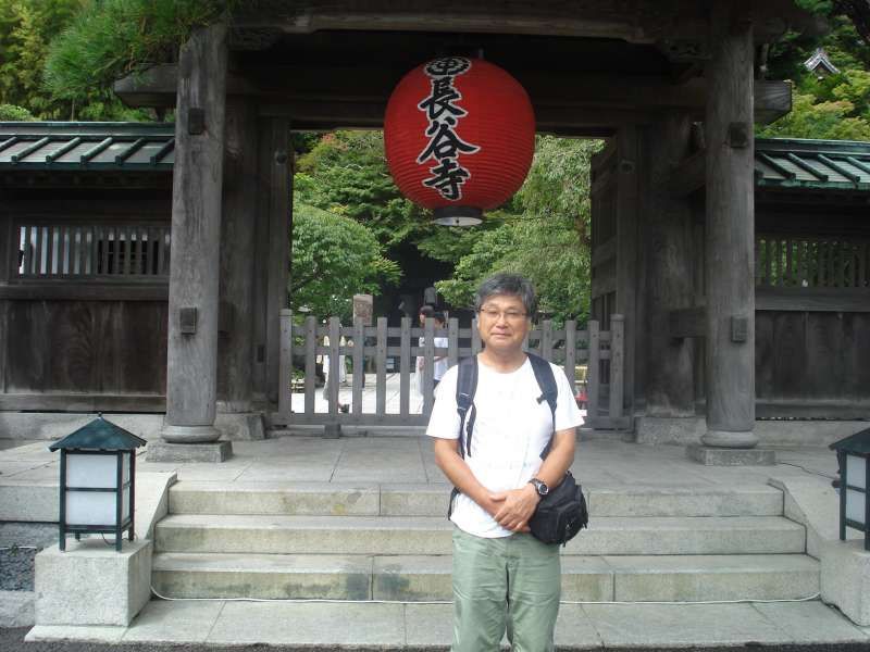 Kanagawa Private Tour - In front of the gate of Hase Temple. In this temple, there is a cave where the image of Benzaiten, or the Goddess of Eloquence, Music, and Art, and those of sixteen Douji, or the attendants of Benzaiten, are laid along the path for visitors. At the end of the steps, a huge golden statue, Hase Kannon, or Hase Goddess of Mercy, stands overlooking visitors. The terrace on which the Goddess is located commands a wide open view of the Yuigahama Beach. 