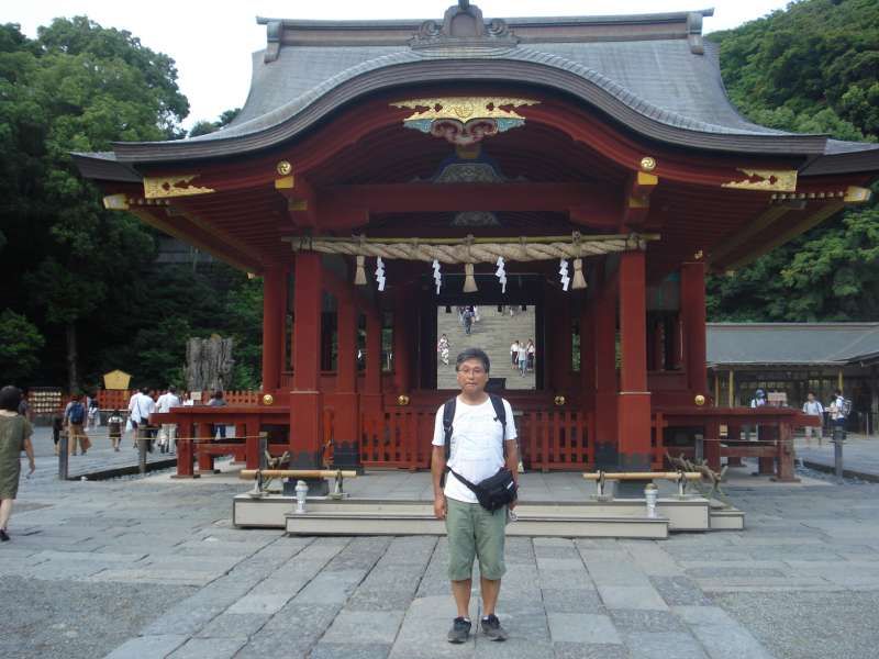 Kanagawa Private Tour - The elavated path called Dankazura leads to Tsurugaoka Hachimangu Shrine. Past the Torii Gate, while crossing the Taiko Bashi Bridge, you see the water of a pond on both sides. On the shrine ground, to the right, there's Kamakura Kokuhoukan, or Kamakura National Treasure Museum. I'm standing in front of Maiden, or court music pavilion of the shrine. We sometimes see wedding ceremonies held in the pavillion. Behind this building, steep stairs lead to Hongu, or the Main Shrine. 