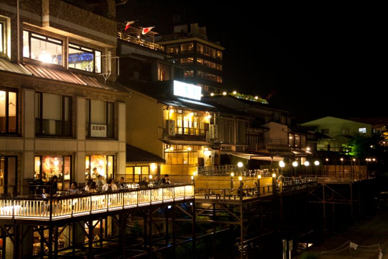 Kyoto Private Tour - The view of restaurants set up on the protruding verandahs on the Kamogawa River bank.  Fresh summer-time dishes are served including fish dishes caught in and near Kyoto City.