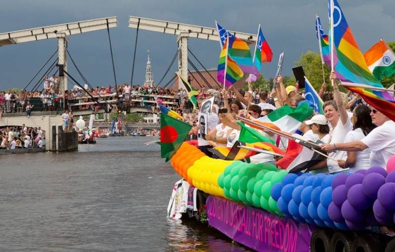 Amsterdam Private Tour - Amsterdam Pride scene at river Amstel with Magere brug (Skinny bridge) behind, for sure most famous bridge in Amsterdam