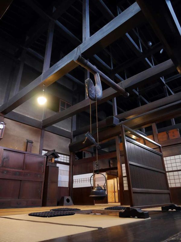 Gifu Private Tour - A main private living room in Kusakabe House. The solid sooted timbers provide an impressive atmosphere with antique furniture and tools around the hearth.  