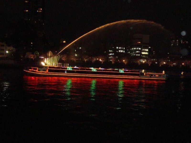 Osaka Private Tour - The fountain is squirting and aqua liner boat is cruising at night