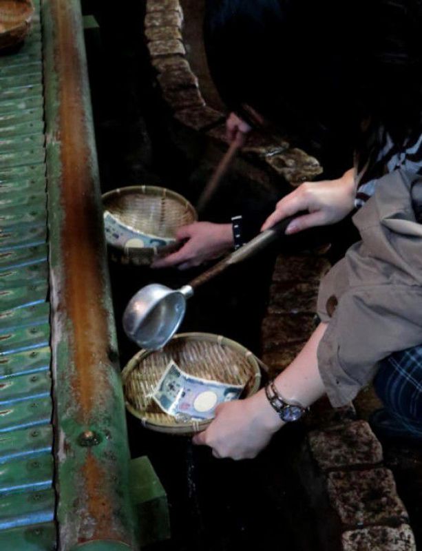 Kamakura Private Tour - Zeniarai Benten.  Pouring sacred water on to bills and coins in a cave