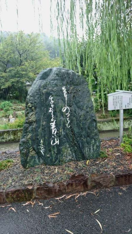 Ehime Private Tour - Along the way from Dogo to Ishiteji Temple, you will find some haiku monuments. This is one of them. This monument is built for a famous poet Santoka Taneda, who is said to have been a wandering poet because of his life style.  He was not born here but settled here in his final days and died here. Today there are many who love his haiku. The haiku inscribed here reads in Japanese, "wake ittemo, wake ittemo, aoi yama." Its meaning is, "deeper and deeper, moving into the area, yet I am still green mountain." This is typical of his style. A weeping willow suits well at a river bank.