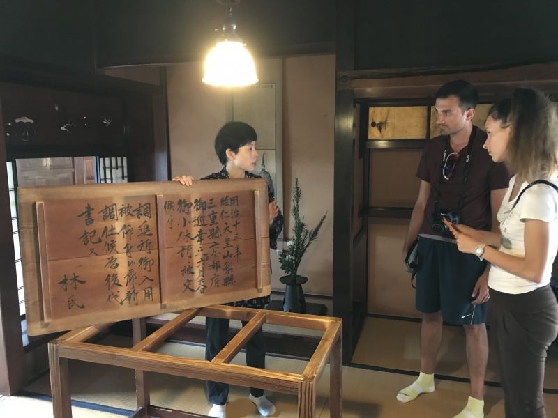 Gifu Private Tour - A female member of staff is explaining the record relating to the short stay of the Meiji emperor in English, which was written on the back of the table.