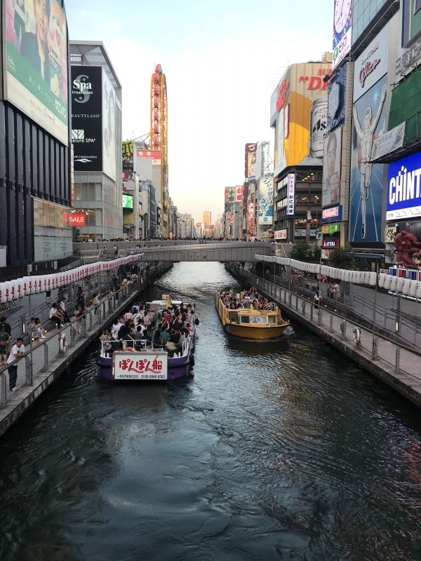 Osaka Private Tour - Se cruzan barcos turísticos dentro de los edificios.