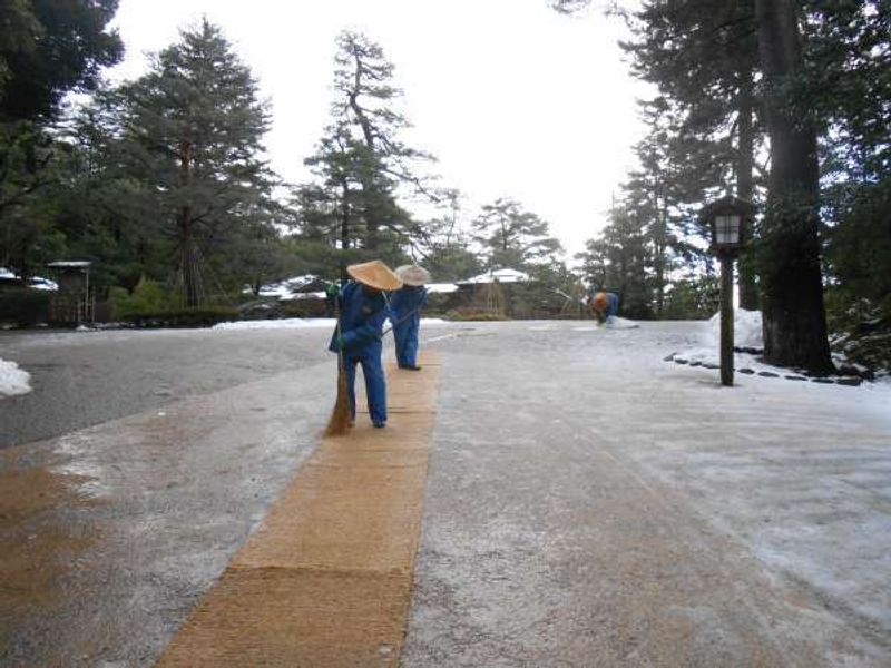 Kanazawa Private Tour - Sweeping the snowy path at Kenrokuen garden.