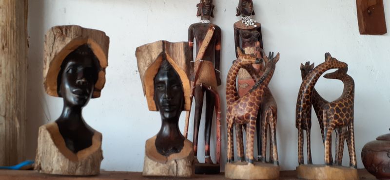 Wood carvings of women with headwraps and a couple of giraffes.