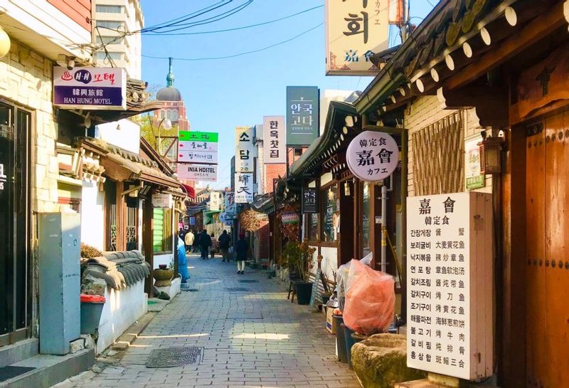 Seoul Private Tour - an alley of Insa-dong traditional-culture street, with Cheondo-gyo Cathedral spire in back