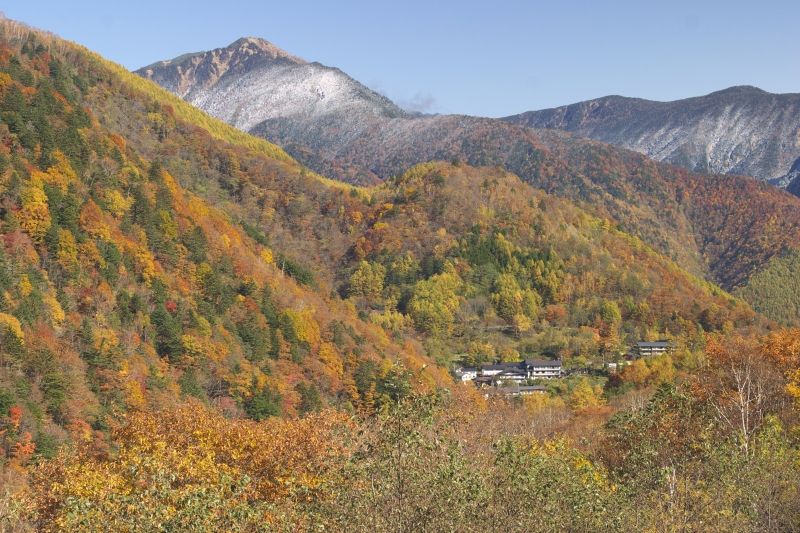 Shirahone Onsen among the mountains. In the fall, there is the view of the beautiful autumn colors and the snow-capped Mt. Norikura.