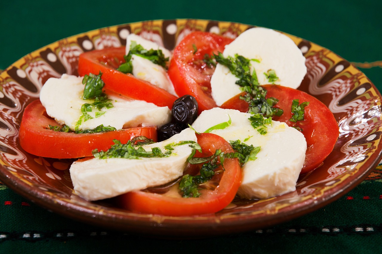 A caprese salad with mozzarella, tomatoes, basil, oregano and olive oil on a plate